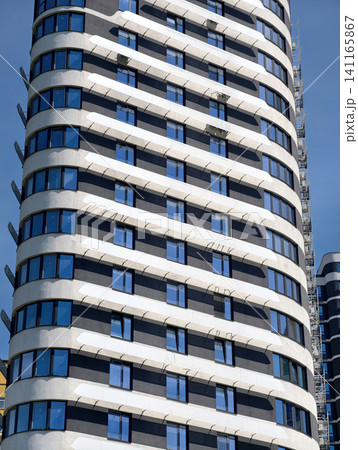 Beautiful urban skyscraper with contemporary residential architecture against clean blue summer sky 141165867