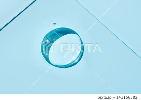 Transparent serum droplet falling on light blue surface 141166582