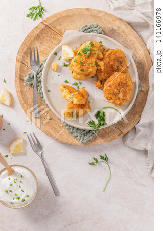 Crispy golden cod fritters on a rustic plate with fresh parsley, lemon, and a creamy dipping sauce, a perfect savory Mediterranean snack Crispy golden cod fritters on a rustic plate with fresh parsley, lemon, and a creamy dipping sauce, a perfect savory Mediterranean snack 141166978