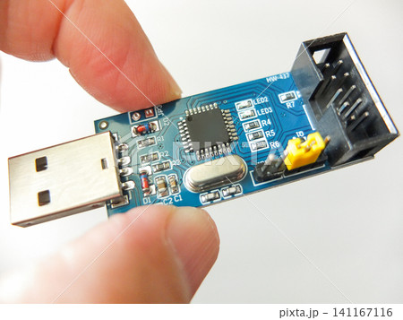 Hand holding a blue electronic PCB board with USB interface and IDC connector. Hand holding a blue electronic PCB board with USB interface and IDC connector. 141167116