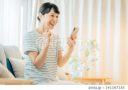 リビングでスマホを操作するミドル女性 141167185