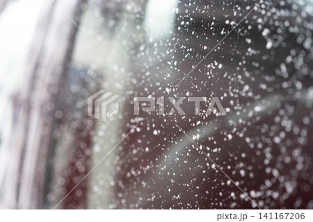 Close-up of a car window covered with scattered snowflakes and ice crystals. Close-up of a car window covered with scattered snowflakes and ice crystals. 141167206