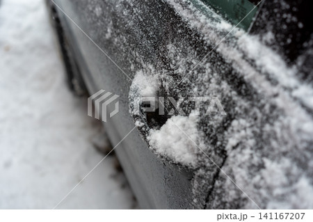 Close-up of a car door handle partially filled with snow and surrounded by frost. Close-up of a car door handle partially filled with snow and surrounded by frost. 141167207