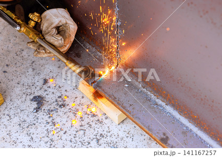Person uses torch to cut metal in workshop at construction site Person uses torch to cut metal in workshop at construction site 141167257