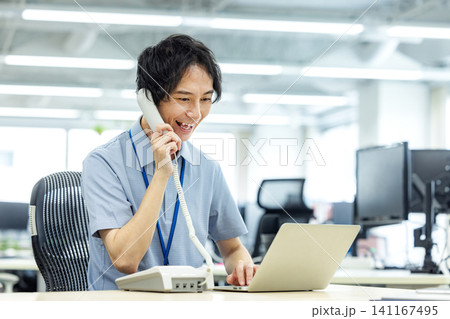 オフィスで固定電話で話をするビジネスマン オフィスで固定電話で話をするビジネスマン 141167495