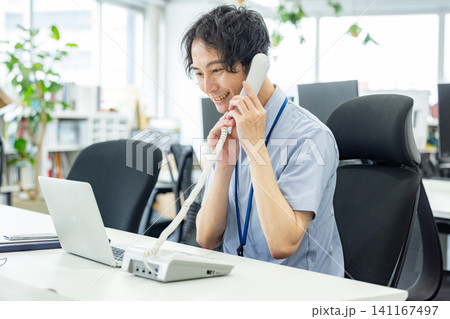 オフィスで固定電話で話をするビジネスマン 141167497