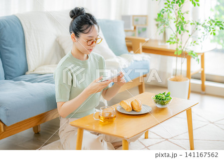 朝ごはんの時にスマホを見る若い女性 141167562