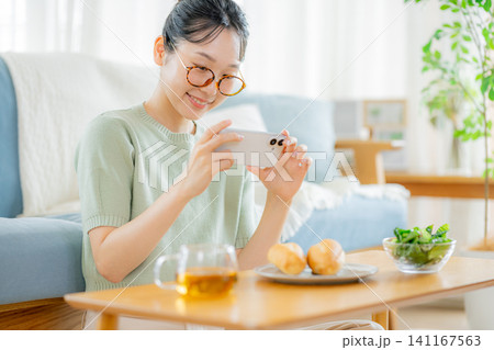 朝ごはんの時にスマホを見る若い女性 朝ごはんの時にスマホを見る若い女性 141167563