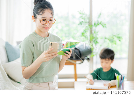 リビングで通帳とスマホを見る母親 リビングで通帳とスマホを見る母親 141167576