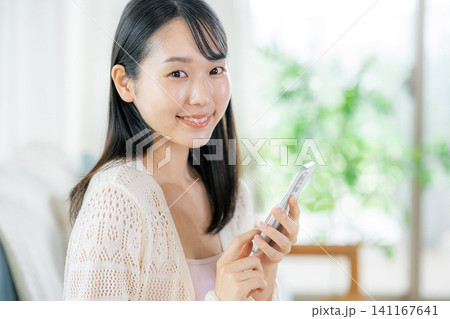 部屋でスマホを見る女性 部屋でスマホを見る女性 141167641