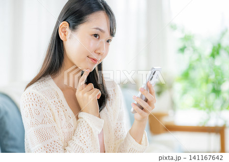 部屋でスマホを見る女性 部屋でスマホを見る女性 141167642