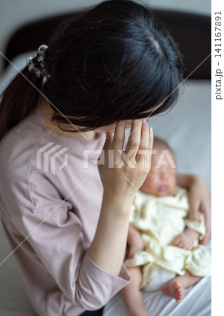 赤ちゃんを抱いた産後疲れの出た新米ママさん 赤ちゃんを抱いた産後疲れの出た新米ママさん 141167891