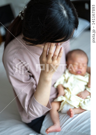 赤ちゃんを抱いた産後疲れの出た新米ママさん 赤ちゃんを抱いた産後疲れの出た新米ママさん 141167893