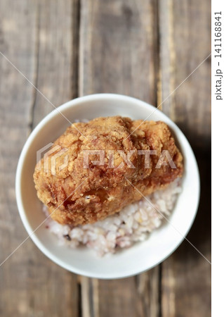 ご飯の上に乗せたカリッとジューシーな鶏もも肉の大きな唐揚げ ご飯の上に乗せたカリッとジューシーな鶏もも肉の大きな唐揚げ 141168841
