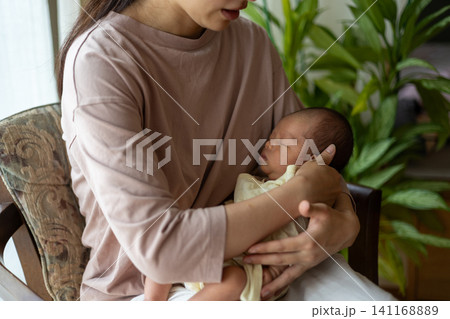 寝ている新生児を抱っこしている若い母親 寝ている新生児を抱っこしている若い母親 141168889