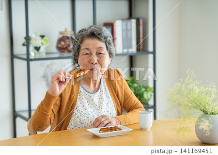 家でみたらし団子を食べるシニアの女性 141169451