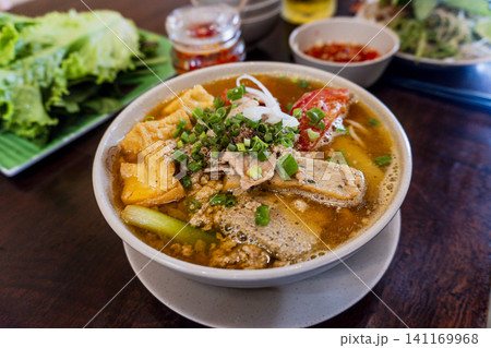 Traditional Vietnamese crab and tomato noodle soup (Bun rieu) served with fried tofu, meat pork paste, and fresh herbs. Traditional Vietnamese crab and tomato noodle soup (Bun rieu) served with fried tofu, meat pork paste, and fresh herbs. 141169968