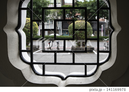 View of a quiet city street and parked bicycles framed through a traditional geometric lattice window at Chiang Kai-shek Memorial Hall in Taipei, Taiwan. View of a quiet city street and parked bicycles framed through a traditional geometric lattice window at Chiang Kai-shek Memorial Hall in Taipei, Taiwan. 141169978