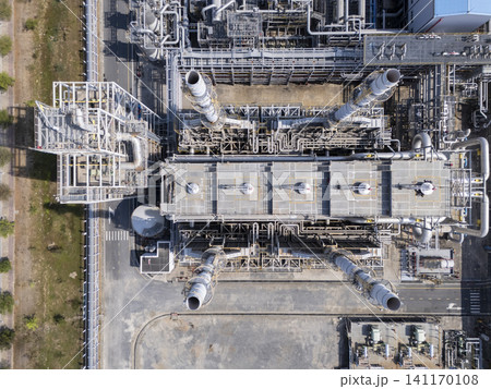 Top-down aerial view of complex industrial pipelines and chimney stacks at a modern power plant or factory. Top-down aerial view of complex industrial pipelines and chimney stacks at a modern power plant or factory. 141170108