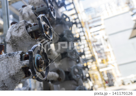 Close-up shot of industrial handwheel valves and insulated pipelines inside a chemical plant or refinery. Close-up shot of industrial handwheel valves and insulated pipelines inside a chemical plant or refinery. 141170126