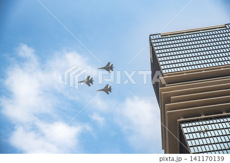Fighter jets flying in formation above a modern high-rise building in Ho Chi Minh City, Vietnam, during an urban aviation event 141170139