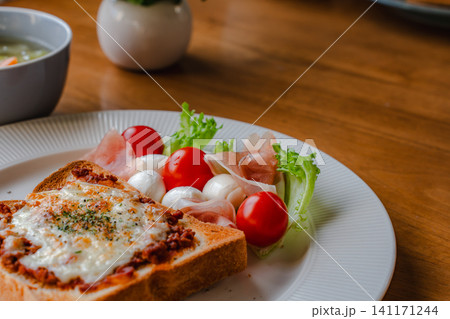 とろけるチーズトーストと生ハムモッツァレラサラダの美味しそうな盛り付け 141171244