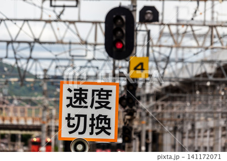 鉄道の速度切換標識と赤信号と駅構内の風景(望遠レンズによる背景ボケ) 鉄道の速度切換標識と赤信号と駅構内の風景(望遠レンズによる背景ボケ) 141172071