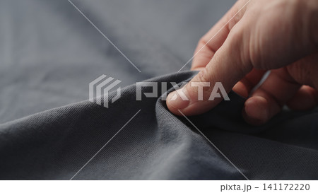 man manually check gray blue color cotton fabric for clothing with hands 141172220