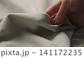man manually check ivory color cotton fabric for clothing with hands 141172235