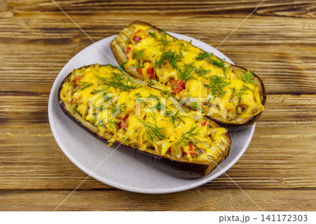 Baked stuffed eggplants on a wooden table. Healthy food and dieting concept Baked stuffed eggplants on a wooden table. Healthy food and dieting concept 141172303