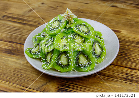 Christmas tree shaped fruit salad on wooden table. Creative idea for Christmas and New Year festive desserts. Funny food idea for kids Christmas tree shaped fruit salad on wooden table. Creative idea for Christmas and New Year festive desserts. Funny food idea for kids 141172321