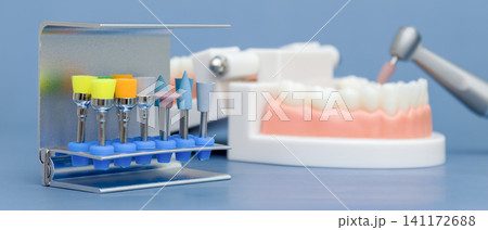 Panoramic web banner of colorful dental polishing brushes in a bur block and a blurred jaw model. Blue background with copy space. 141172688