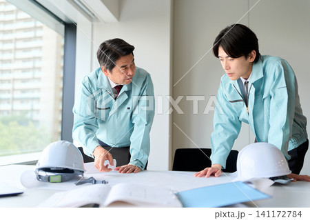 打ち合わせをする作業服を着た男性 打ち合わせをする作業服を着た男性 141172784