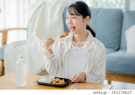 リビングでお弁当を食べる若い女性 141174627
