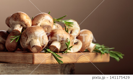 Mushrooms with rosemary on a wooden cutting board. 141175429