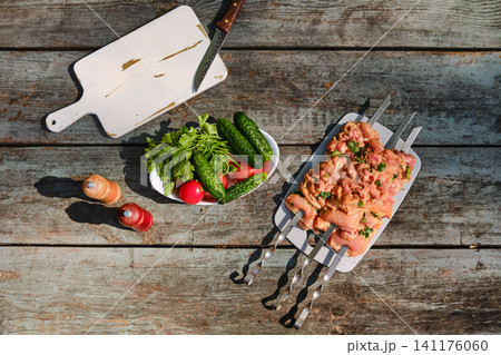 Top view of chicken skewers on wooden table with vegetables and knife Top view of chicken skewers on wooden table with vegetables and knife 141176060