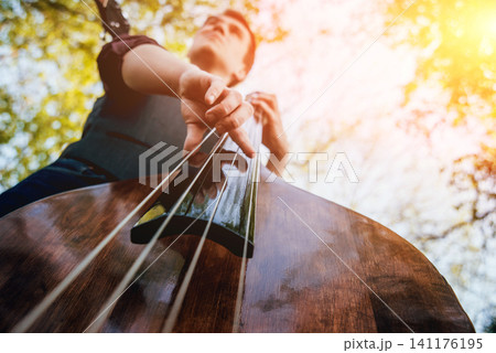View of musician playing contrabass at the street. Musical Instrument View of musician playing contrabass at the street. Musical Instrument 141176195