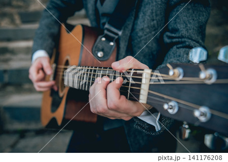 Man's hands playing acoustic guitar. Background 141176208