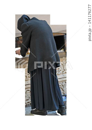 Elderly orthodox nun or pilgrim walking isolated on transparent background. Back view of senior christian woman in black habit, headscarf and long dress. Monastery lifestyle and cathedral cutout 141176277