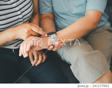 Close up of Asian woman checking smartwatch on wrist at home, concept of health tracking, wearable technology, fitness monitor, digital healthcare, and daily wellness. Close up of Asian woman checking smartwatch on wrist at home, concept of health tracking, wearable technology, fitness monitor, digital healthcare, and daily wellness. 141177001