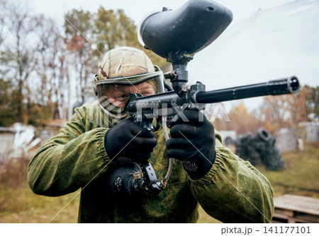 Man with gun playing at paintball. Outdoors Man with gun playing at paintball. Outdoors 141177101