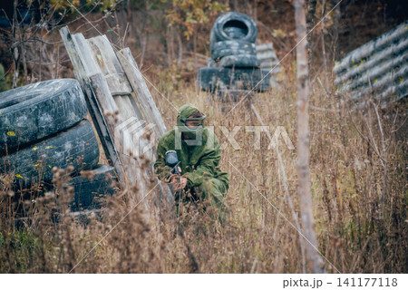 Man with gun playing at paintball. Outdoors Man with gun playing at paintball. Outdoors 141177118