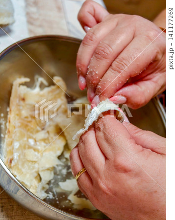 Hands deshelling salted cod for traditional cooking 141177269