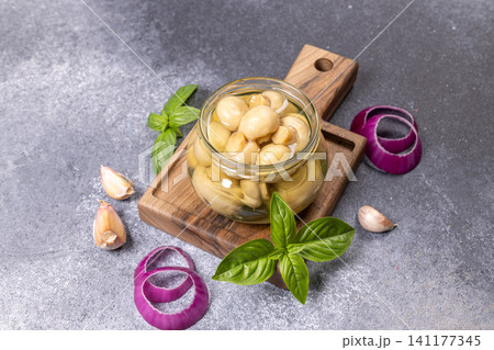 Pickled button mushrooms in jar on wooden board Pickled button mushrooms in jar on wooden board 141177345