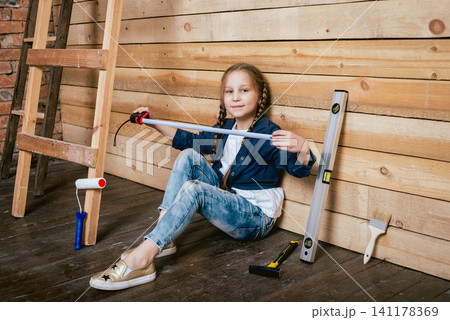 Little girl in a room with a wooden wall. Construction Little girl in a room with a wooden wall. Construction 141178369