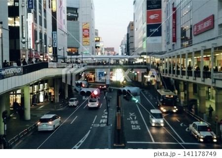 日暮れ前の駅前を行き交う車と人々。街の灯りが少しずつ灯り始める都市風景。 141178749