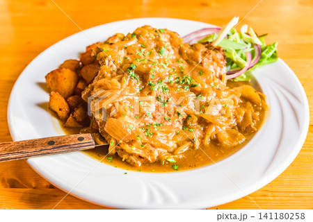 ローストポテトを添えたオーストリア伝統の肉料理ツヴィーベルローストブラーテンのオニオンステーキ ローストポテトを添えたオーストリア伝統の肉料理ツヴィーベルローストブラーテンのオニオンステーキ 141180258