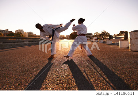 People, karate and fitness with personal trainer in city street for self defense, fighting technique or style. Man and woman fighter or athlete in training, martial arts or kick boxing in urban town People, karate and fitness with personal trainer in city street for self defense, fighting technique or style. Man and woman fighter or athlete in training, martial arts or kick boxing in urban town 141180511