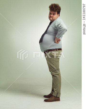 Business man, portrait and plus size with unhappy, sad and frustrated in studio with arms on hips. Job, employee and office fashion with problem and clothing with green background and moody from work 141180797