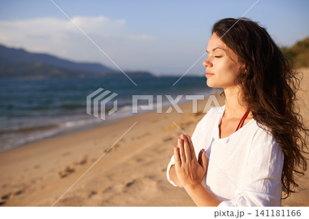 Prayer hands, woman and meditation on beach with mindfulness, eyes closed and zen with fresh air for calm outdoor. Ocean, breeze and travel with yoga for health, peace of mind and holistic healing Prayer hands, woman and meditation on beach with mindfulness, eyes closed and zen with fresh air for calm outdoor. Ocean, breeze and travel with yoga for health, peace of mind and holistic healing 141181166